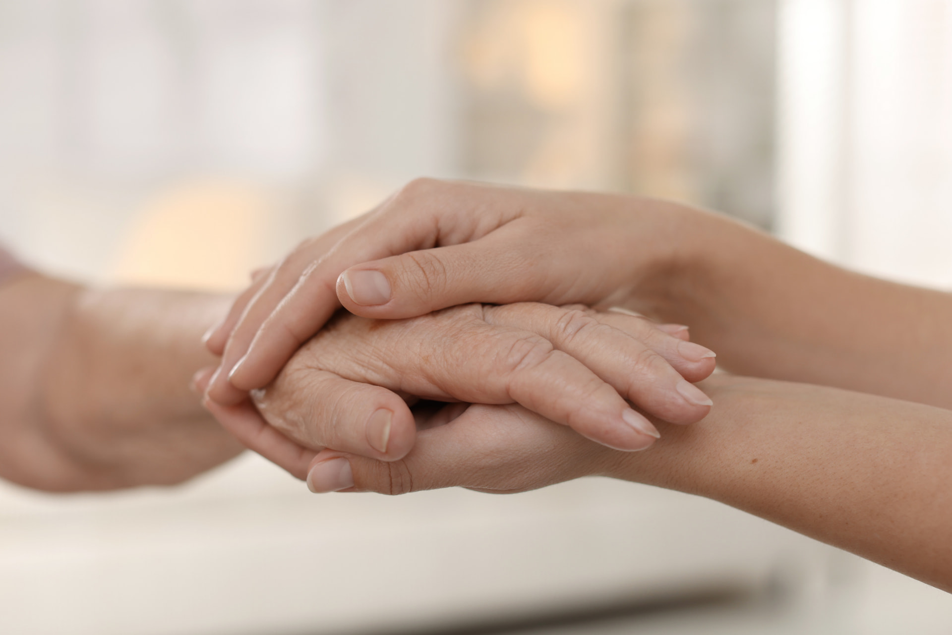 Dos manos sosteniendo con cariño la mano de una persona mayor